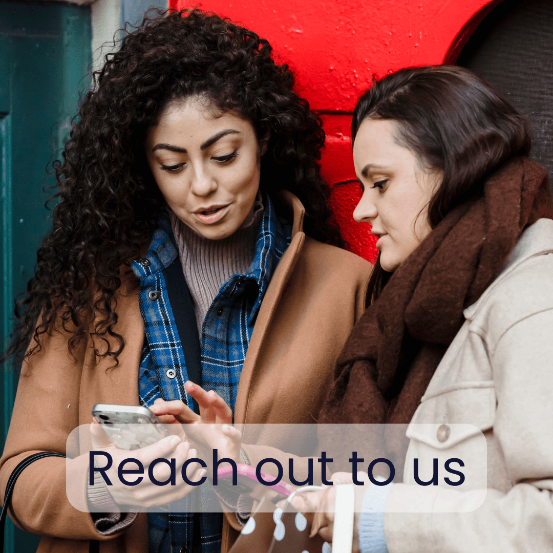 young woman with naturally curly hair showing her friend something on her phone